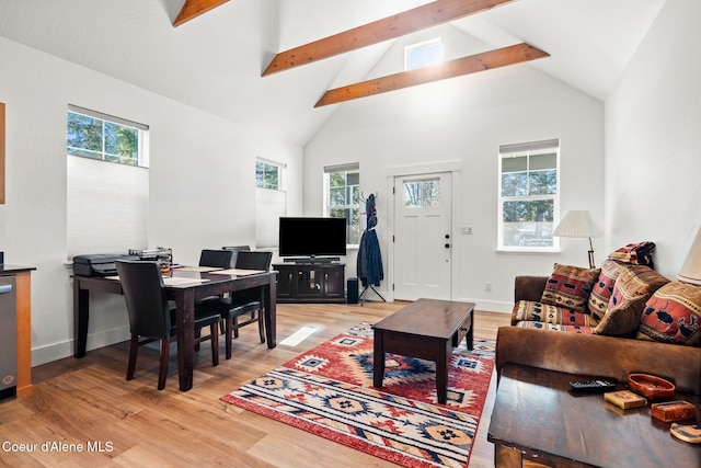 living room with a healthy amount of sunlight, beam ceiling, high vaulted ceiling, and light hardwood / wood-style flooring