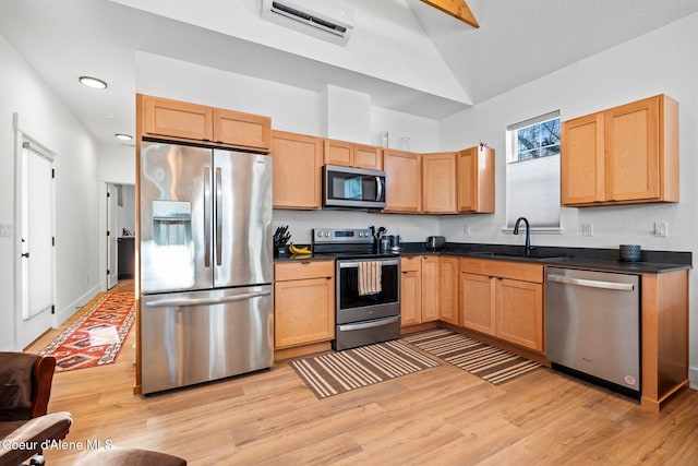 kitchen featuring appliances with stainless steel finishes, sink, lofted ceiling, and light hardwood / wood-style flooring