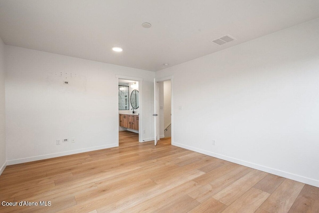 unfurnished bedroom featuring ensuite bath and light hardwood / wood-style floors