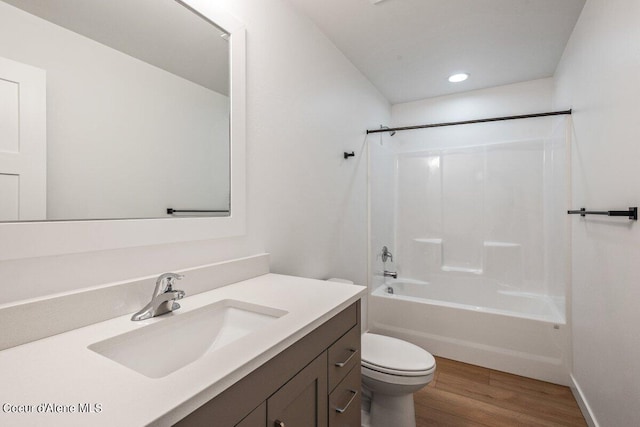 full bathroom with hardwood / wood-style flooring, vanity, washtub / shower combination, and toilet