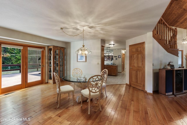 dining area with wine cooler, an inviting chandelier, and light hardwood / wood-style flooring