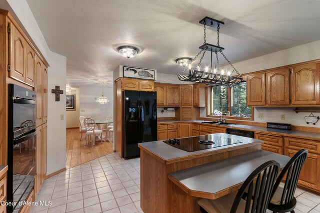kitchen featuring hanging light fixtures, light tile patterned floors, black appliances, and a center island