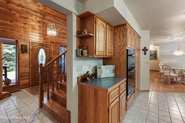 kitchen featuring light tile patterned flooring, wood walls, hanging light fixtures, and a notable chandelier
