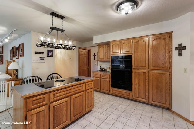 kitchen featuring light tile patterned flooring, decorative light fixtures, a kitchen island, and black appliances
