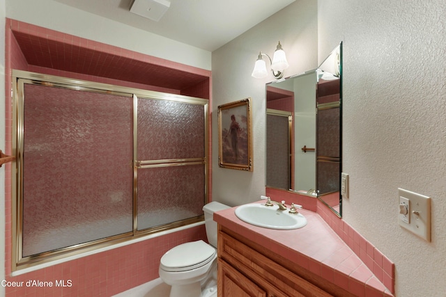 full bathroom featuring vanity, combined bath / shower with glass door, and toilet