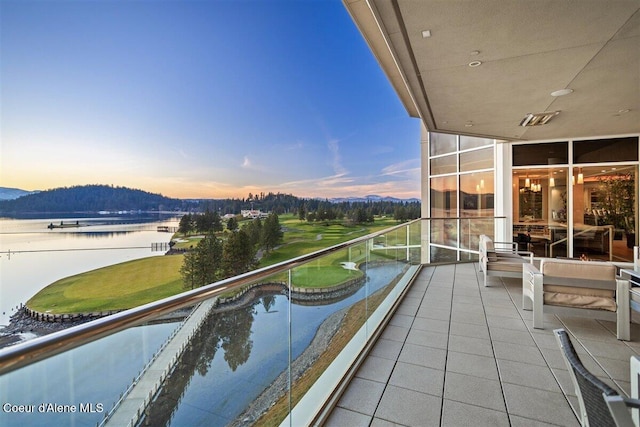 balcony at dusk featuring a water view