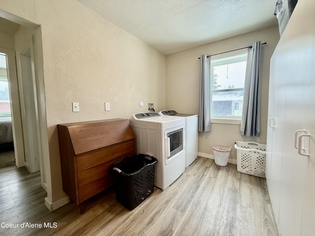 clothes washing area with separate washer and dryer, light hardwood / wood-style floors, and a textured ceiling