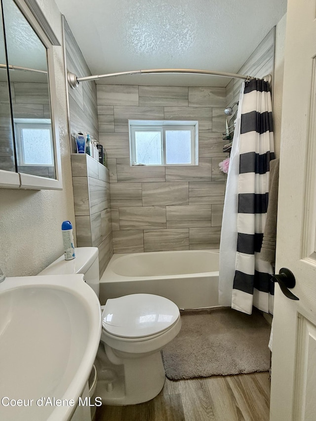 full bathroom with hardwood / wood-style floors, sink, toilet, a textured ceiling, and shower / bath combo with shower curtain