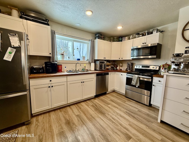 kitchen featuring sink, light hardwood / wood-style floors, white cabinets, and appliances with stainless steel finishes