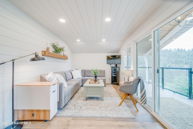 living room featuring wooden walls, a wealth of natural light, wooden ceiling, and light hardwood / wood-style floors