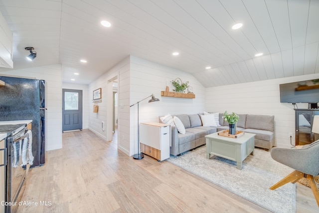 living room with lofted ceiling, light hardwood / wood-style floors, and wood walls