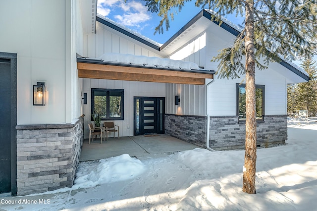 snow covered property entrance with covered porch