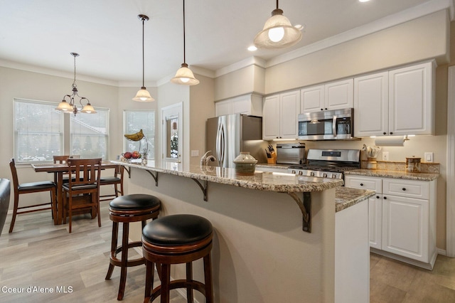 kitchen with light stone counters, white cabinetry, decorative light fixtures, and appliances with stainless steel finishes