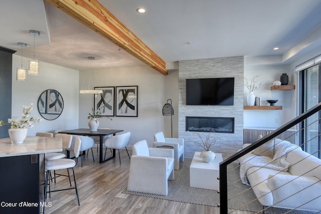 living room featuring hardwood / wood-style flooring, a stone fireplace, and beam ceiling