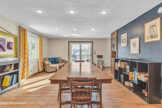 dining space featuring french doors, plenty of natural light, light hardwood / wood-style flooring, and a textured ceiling