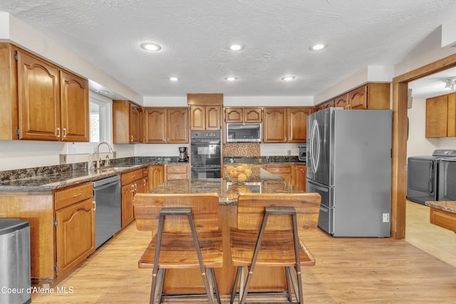 kitchen with stainless steel appliances, a center island, sink, and light hardwood / wood-style floors