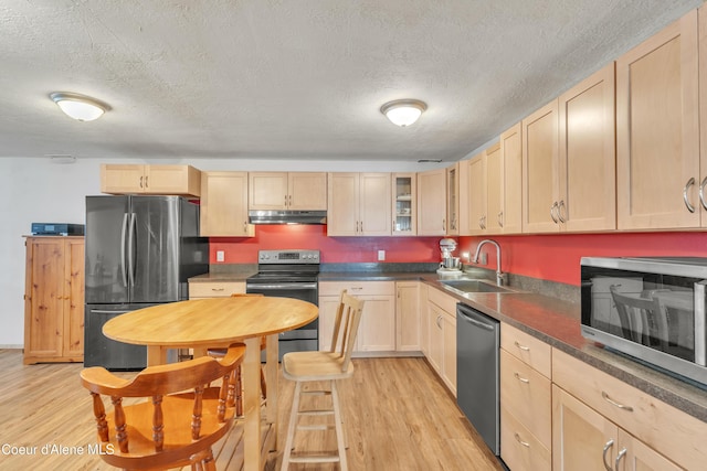 kitchen featuring sink, stainless steel appliances, a textured ceiling, light brown cabinetry, and light wood-type flooring