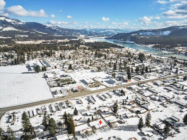 snowy aerial view featuring a water and mountain view