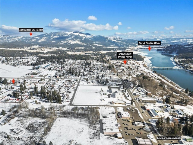 snowy aerial view featuring a water and mountain view