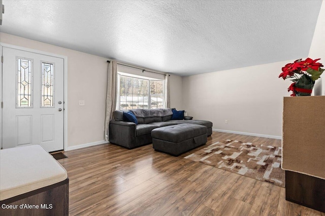 living room featuring a textured ceiling, baseboards, and wood finished floors