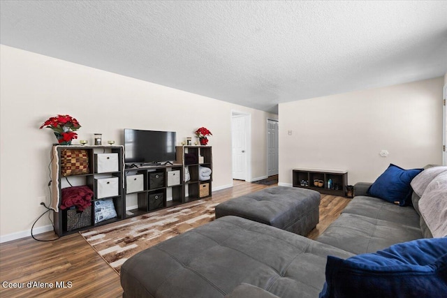 living room with a textured ceiling, baseboards, and wood finished floors