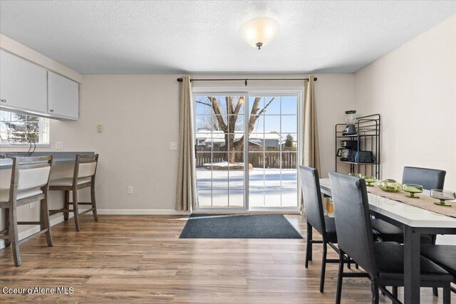 dining area featuring a textured ceiling, plenty of natural light, baseboards, and light wood-style floors