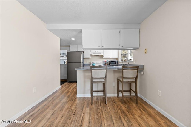 kitchen featuring plenty of natural light, white cabinets, a breakfast bar area, a peninsula, and stainless steel appliances