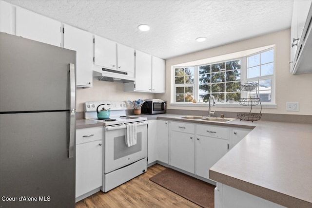 kitchen with stainless steel appliances, light countertops, under cabinet range hood, white cabinetry, and a sink