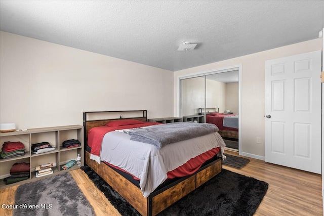 bedroom featuring a textured ceiling, a closet, wood finished floors, and baseboards