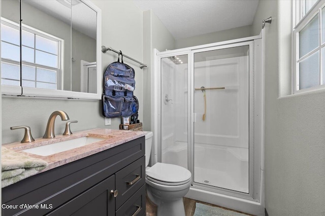 bathroom with a stall shower, vanity, toilet, and a textured ceiling