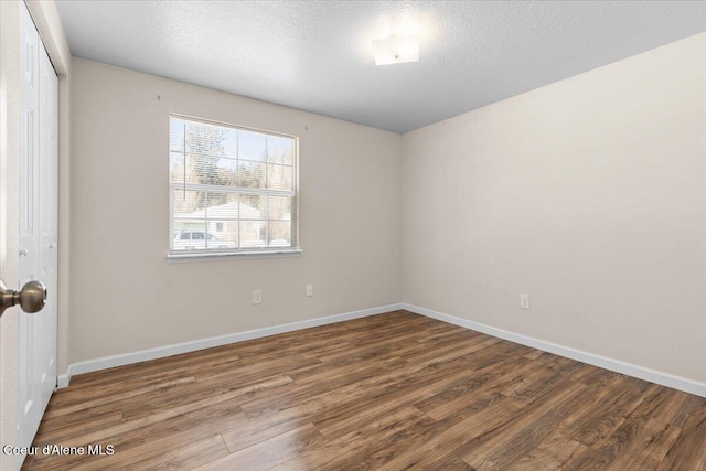 spare room with dark wood-style floors, baseboards, and a textured ceiling