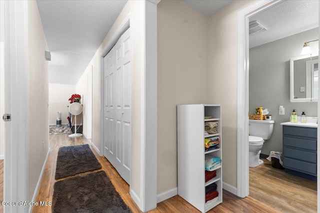 hallway featuring light wood-type flooring, visible vents, and baseboards