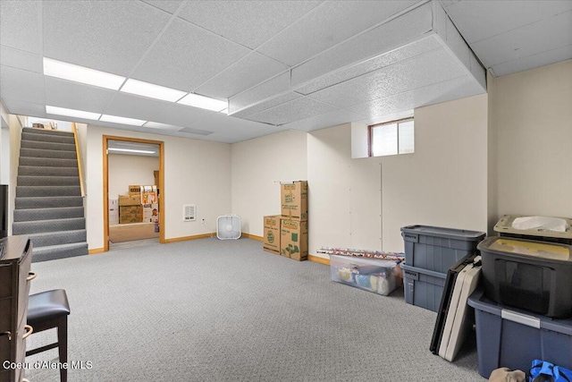 below grade area featuring a paneled ceiling, baseboards, stairway, and carpet flooring