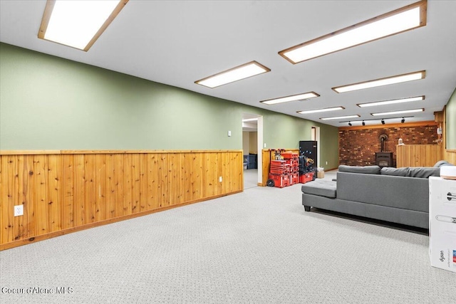 carpeted living room with a wainscoted wall, wood walls, and a wood stove