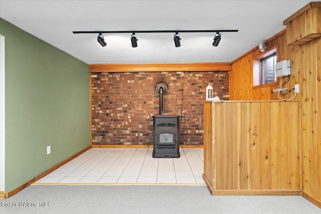 unfurnished living room featuring a wood stove, light carpet, wood walls, and light tile patterned floors