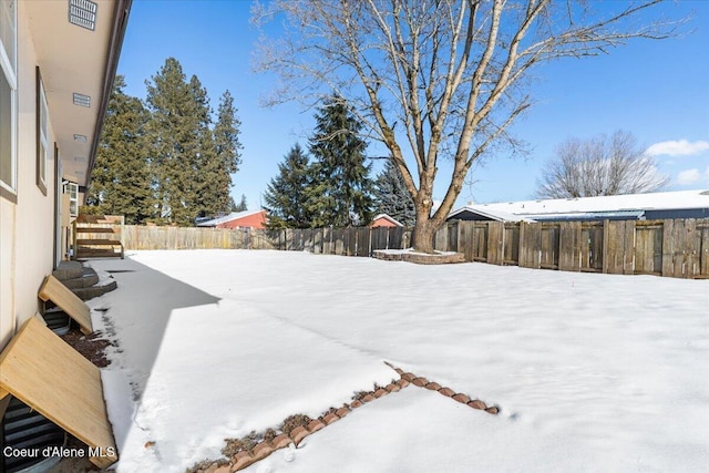 snowy yard featuring a fenced backyard