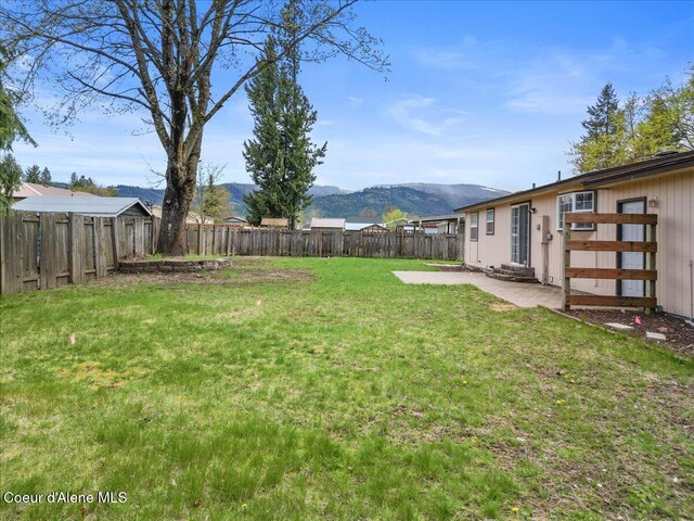 view of yard featuring a patio, a mountain view, and a fenced backyard
