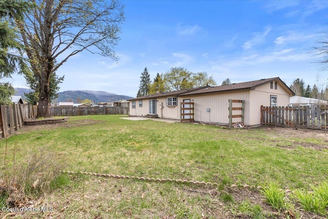rear view of property featuring a fenced backyard, a mountain view, and a yard