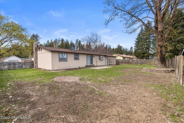 back of property with a patio, a fenced backyard, a yard, and a chimney