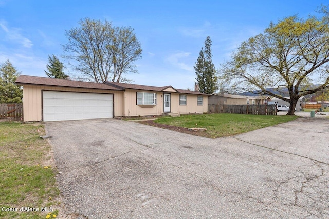 ranch-style home with fence, a garage, a front lawn, and aphalt driveway