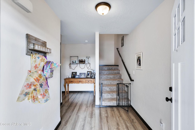 interior space featuring hardwood / wood-style flooring, a textured ceiling, and an AC wall unit