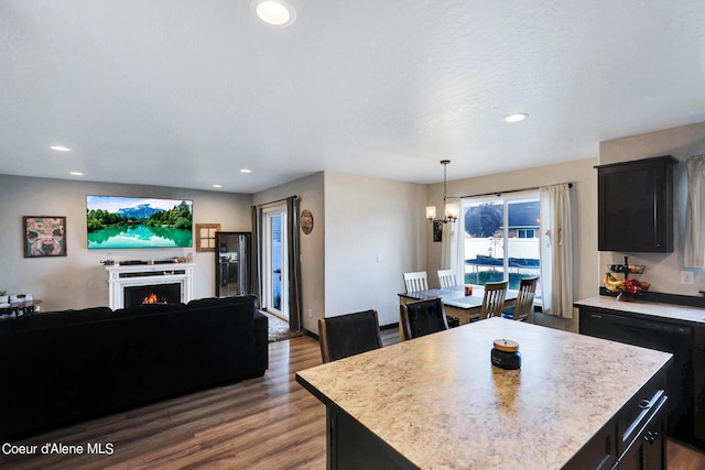 kitchen with pendant lighting, an inviting chandelier, a center island, wood-type flooring, and a textured ceiling