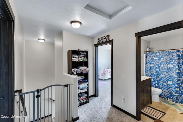 hallway featuring light carpet and a textured ceiling