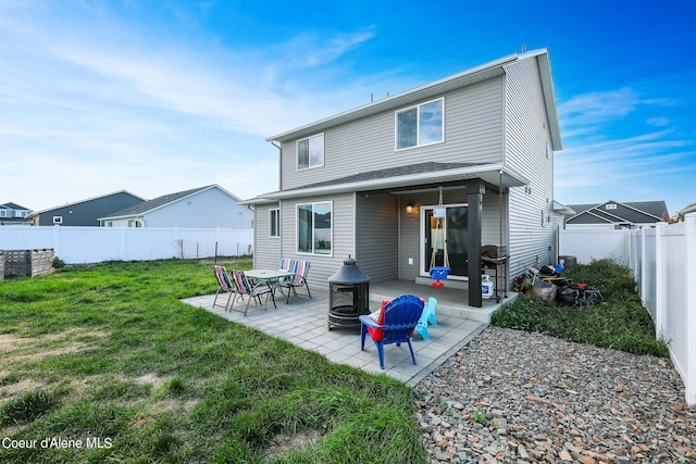 rear view of house with a patio, a lawn, and an outdoor fire pit