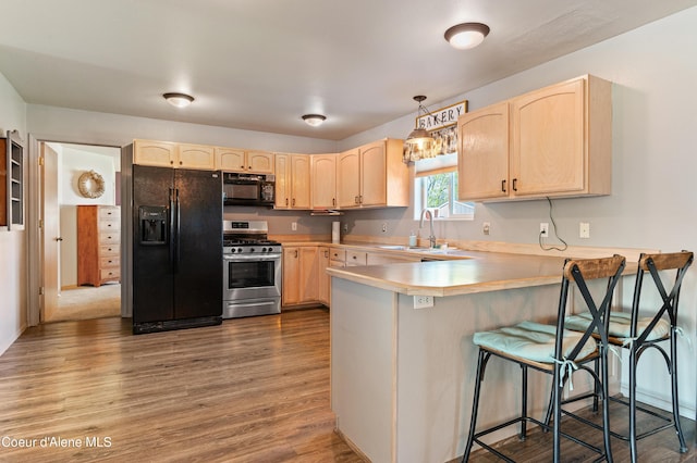 kitchen featuring decorative light fixtures, black appliances, sink, kitchen peninsula, and light brown cabinets