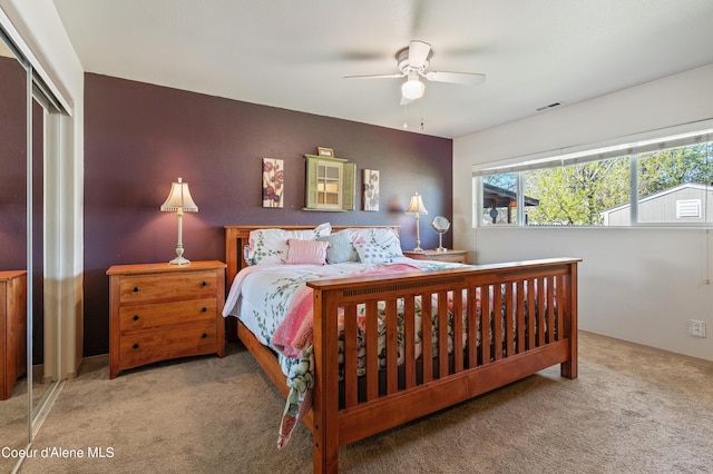 bedroom with light carpet, ceiling fan, and a closet
