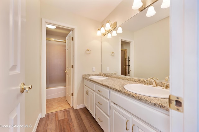 bathroom with hardwood / wood-style flooring, vanity, and combined bath / shower with glass door