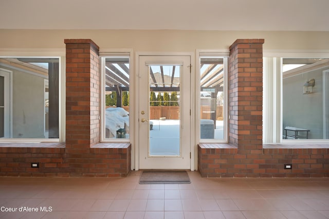 doorway to outside featuring brick wall and tile patterned floors