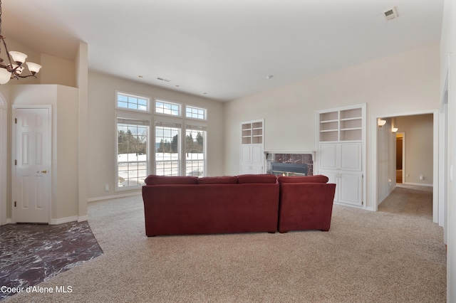 carpeted living room featuring an inviting chandelier and a high end fireplace