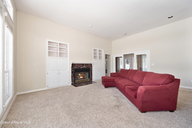 living room with light colored carpet, a fireplace, and built in shelves